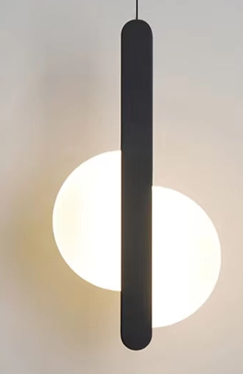 Black bar pendant light with a split round disc, lit, against a pale wall.
