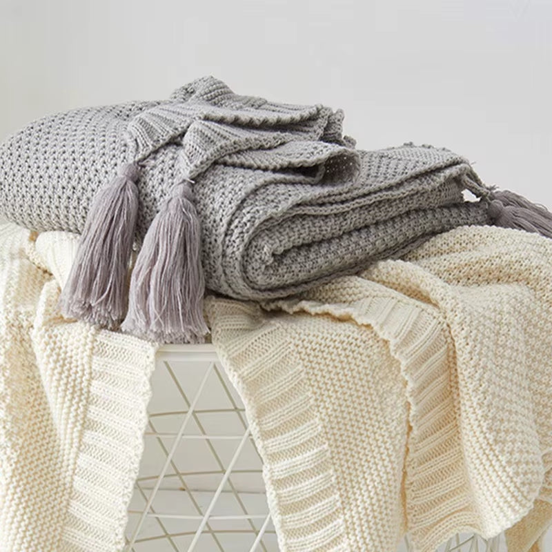 Light gray waffle knit throw folded over a cream throw.