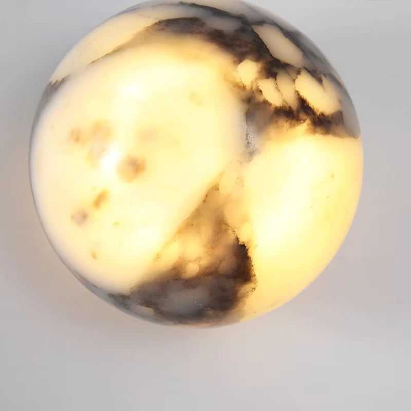 Close view of the marble sphere wall sconce, lit, showing light through the stone.