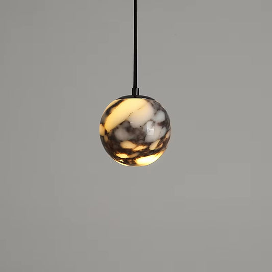 Marble globe pendant light on a black cord, lit, against a gray wall.