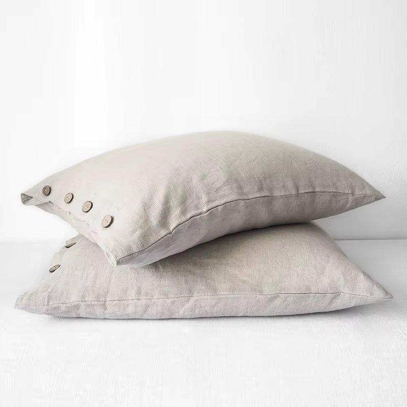 Two natural linen pillow covers with button closures, stacked.