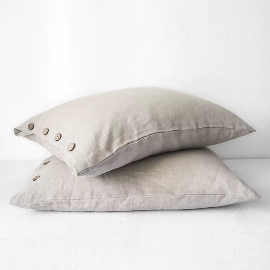 Two natural linen pillow covers with button closures, stacked.