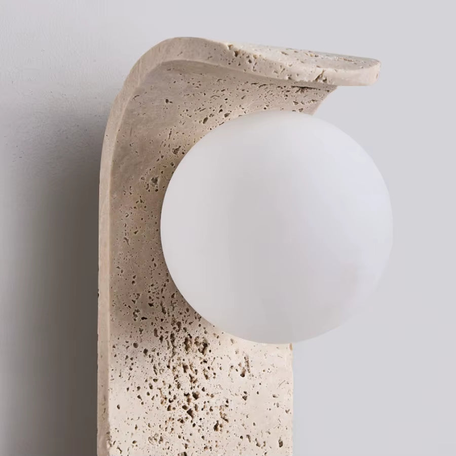 Close view of the white glass globe against the pitted travertine plate