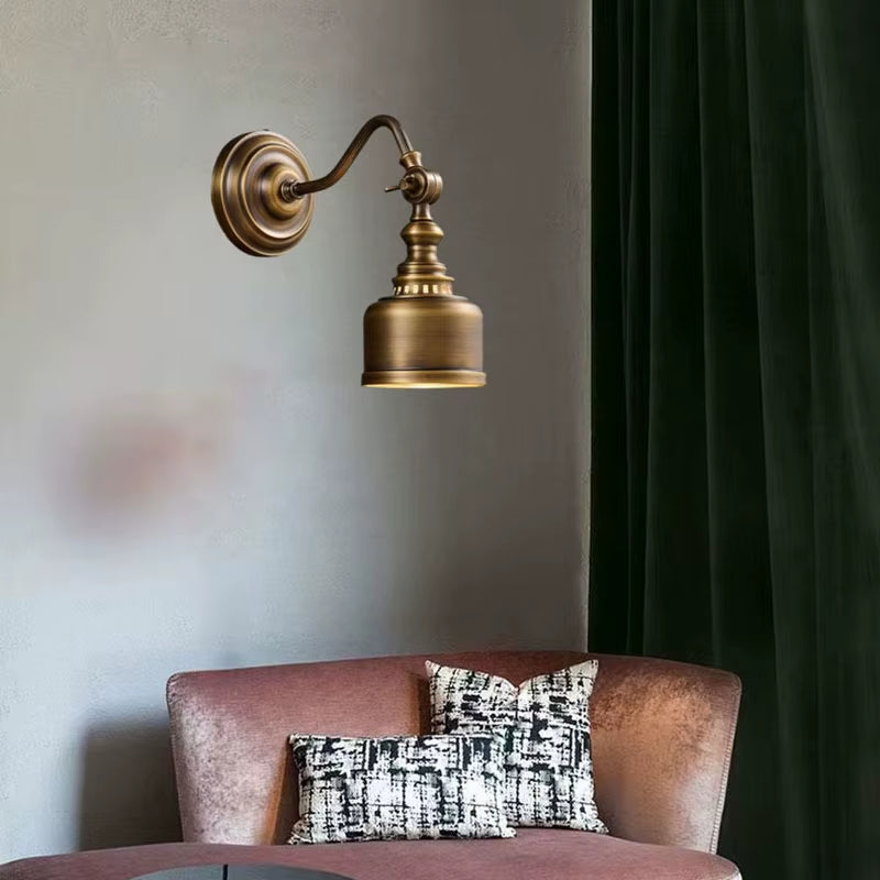 Brass-shade curved arm wall sconce above a chair