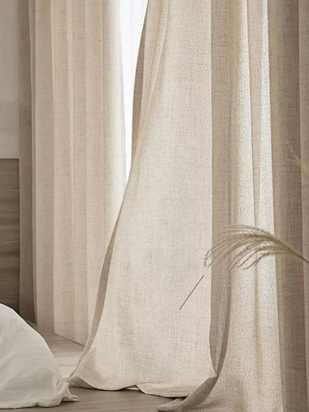 Natural beige cotton-linen curtain panels letting soft daylight into a bedroom.