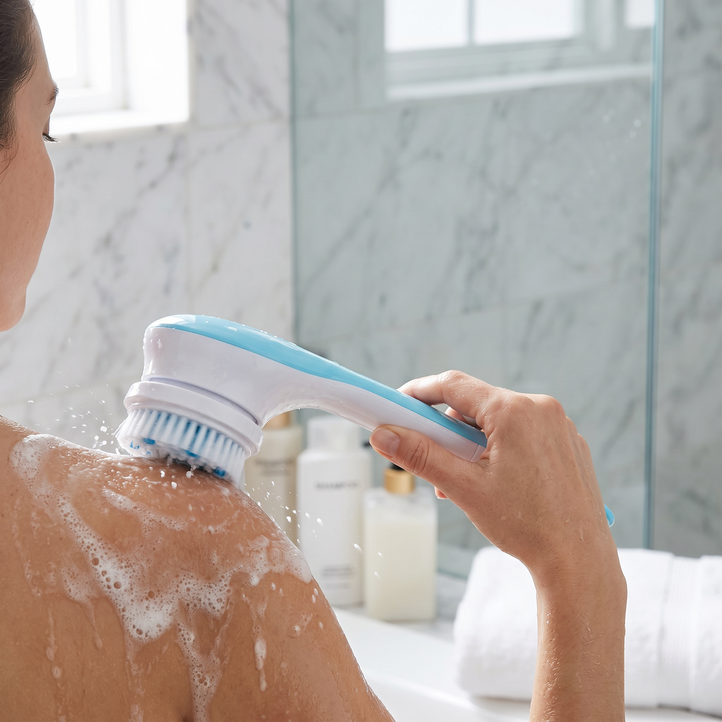 Exfoliating Body Brush — bright marble bathroom shower/vanity area — real-scene lifestyle v4