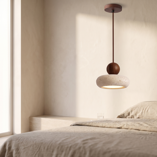 Small pendant light with a walnut-color rod and ball above a rounded cream shade, hanging over a bed.